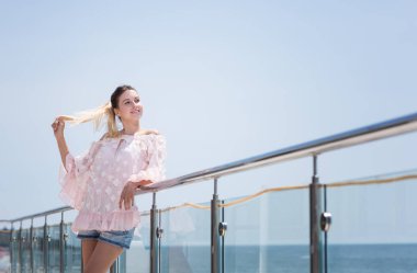 Gülümseyen, çekici ve mutlu bir kadın güneşli yaz keyif alıyor. Parlak mavi gökyüzü arka plan üzerinde şirin model kız.