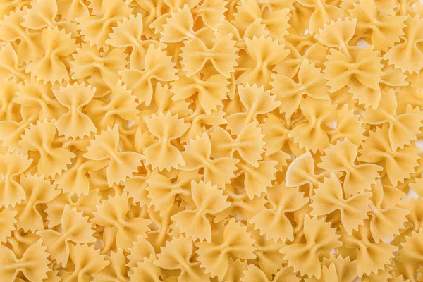 Rohe, köstliche und leuchtend gelbe Textur aus nächster Nähe. Ungekochte italienische Farfalle-Pasta als Hintergrund. Nudeln, Macarons, Nudeln, Spaghetti aus nächster Nähe. — Stockfoto