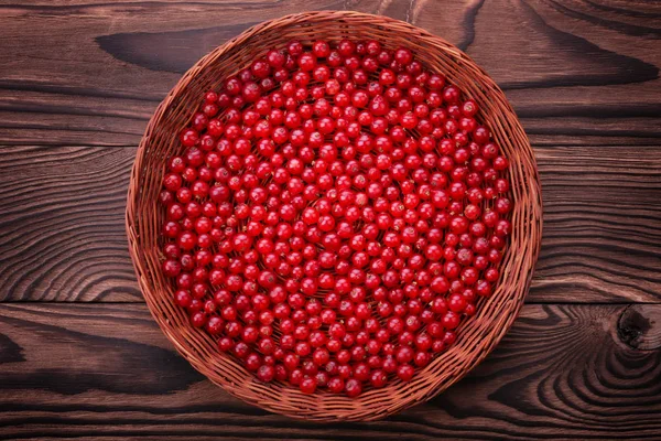 Close-up of a light brown basket filled with a red currant. Fresh tasteful berries on a dark brown wooden background. Bright red currant. — Stock Photo, Image