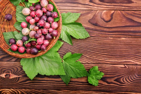 Colorful pink gooseberries full of nutritious vitamins in a wooden basket. The crate with juicy, ripe and healthful berries on the table.