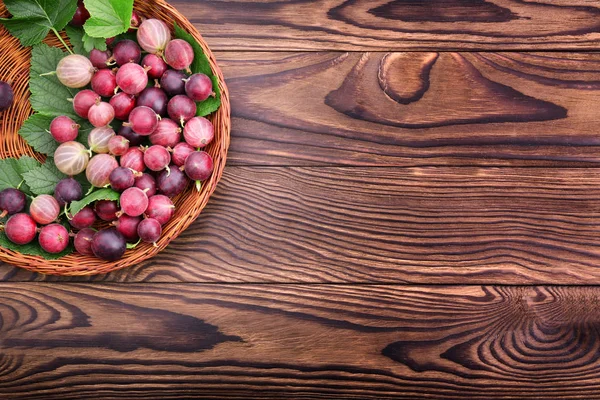 Ahşap arka plan üzerinde parlak kahverengi sandık içinde taze yapraklarla renkli bektaşi organik ve sağlıklı. Renkli ve besleyici çilek.