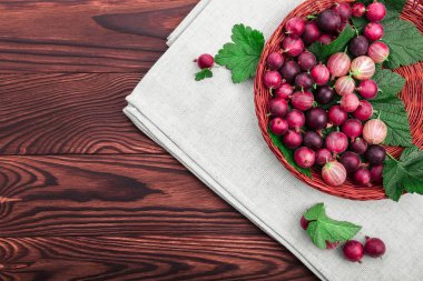 Koyu kahverengi ahşap bir masa üzerinde bir sepet içinde yeşil yaprakları ile çok renkli bektaşi lezzetli, sulu, sağlıklı, olgun. Sulu, ham, taze, lezzetli, sağlıklı, besleyici kavramı.