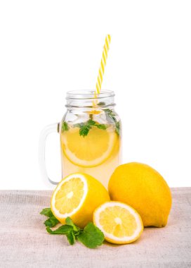 Büyük cam sürahi beyaz bir arka plan üzerinde izole bir hafif kumaş üzerine limonata ve sarı limon ile. Mojito büyük bir kavanoza uzun sarı saman.