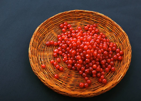 Bright red currant in a wooden basket on a black background. A crate full of berries.  A top view of sour and juicy red current. — Stock Photo, Image