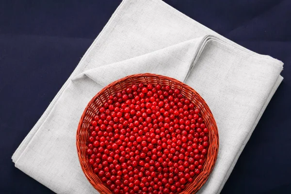 Ein Holzkorb mit roten Johannisbeeren auf dunkelblauem Hintergrund. frische und reife rote Johannisbeeren. Beeren auf grauem Stoff. Bio-Lebensmittel. — Stockfoto