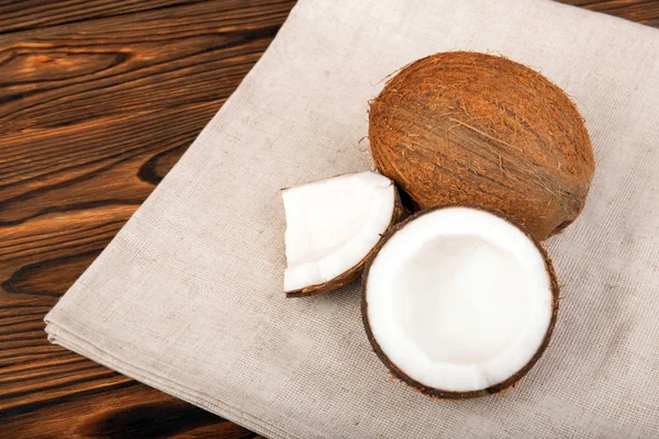 Um close-up de belos cocos em um fundo marrom. Coco recém fatiado em um saco de serapilheira. ingredientes vegetarianos saborosos . — Fotografia de Stock