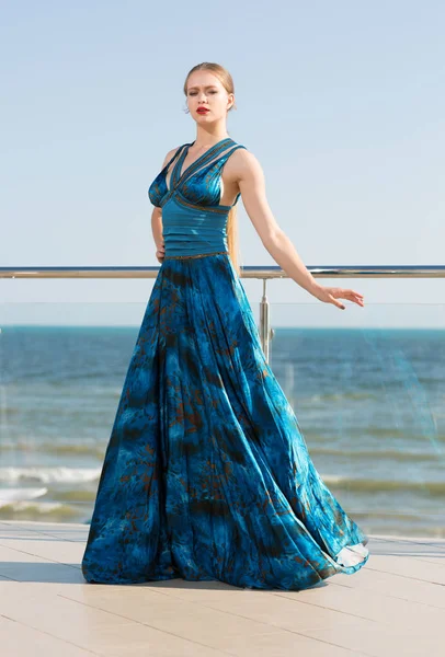 Uzun sallayarak bir zümrüt elbiseli güzel ve zarif bir Bayan parlak mavi denize yakın poz. Tatil çekici kız denizde.
