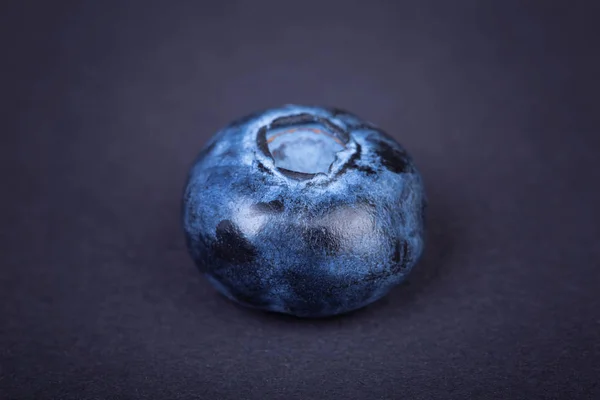 Top view of a juicy, healthful and tasty blueberry on a dark background. Fresh single blueberry fruit, close-up. Summer fruits.