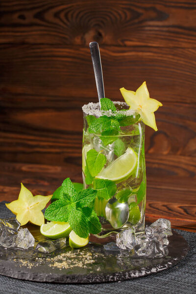 крупным планом свежий напиток с мятными листьями, льдом и лимоном на деревянном фоне
.