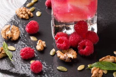 Güzel pembe ahududu. Çilek, ceviz ve güler yüzlü bir siyah arka plan üzerine bir bardak. Sağlıklı, lezzetli, tatlı yaz meyve.