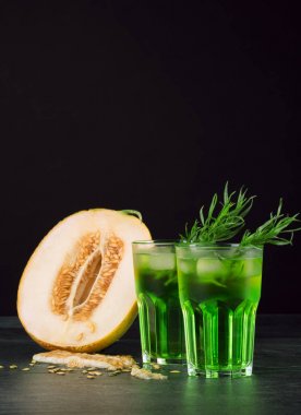 Yeşil alkol kokteyller. Soğuk içecekler ve siyah bir zemin üzerine bir kavun. Tarhun, buz ve tatlı kavun ile içecekler. Kopya alanı.