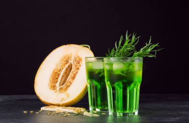 Yeşil alkol kokteyller. Soğuk içecekler ve siyah bir zemin üzerine bir kavun. Tarhun, buz ve tatlı kavun ile içecekler. Kopya alanı.