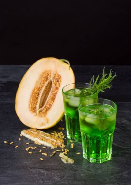 Yeşil alkol kokteyller. Soğuk içecekler ve siyah bir zemin üzerine bir kavun. Tarhun, buz ve tatlı kavun ile içecekler. Kopya alanı.