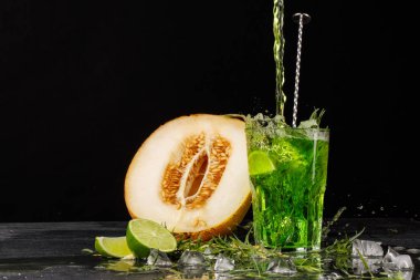 Kireç ve tarhun ile yeşil bir içki. Bir kokteyl ve siyah bir zemin üzerine bir kavun. Sağlıklı, tatlı ve lezzetli içecekler. Kopya alanı.