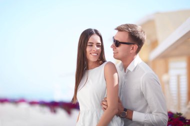 Bir çift bir tatil. Güneşli kıyı arka plan güzel lovers. Çok güzel bir kız ve gülümseyen bir erkek. Kopya alanı.