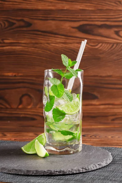 Kalter Mojito mit Eis und Kalk. Grüner Mojito mit Rum oder Likör auf Holzgrund. Erfrischende alkoholische Getränke. Kopierraum. — Stockfoto