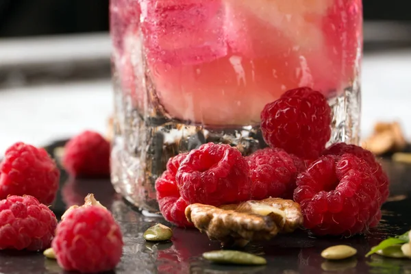 Güzel pembe ahududu. Çilek, ceviz ve güler yüzlü bir tablo arka plan üzerine bir bardak. Sağlıklı, lezzetli, tatlı yaz meyve.