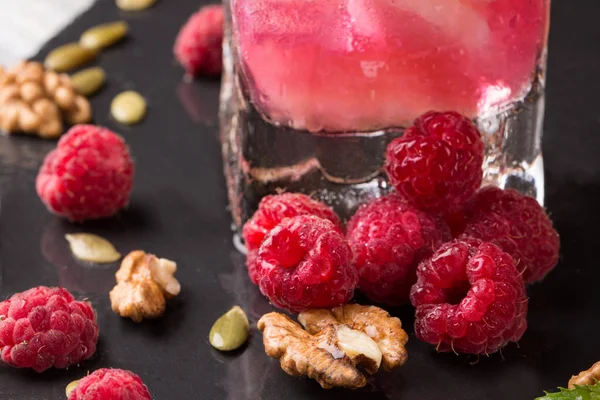 Güzel pembe ahududu. Çilek, ceviz ve güler yüzlü bir siyah arka plan üzerine bir bardak. Sağlıklı, lezzetli, tatlı yaz meyve.