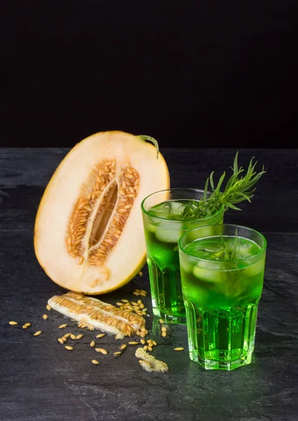 Yeşil alkol kokteyller. Soğuk içecekler ve siyah bir zemin üzerine bir kavun. Tarhun, buz ve tatlı kavun ile içecekler. Kopya alanı.