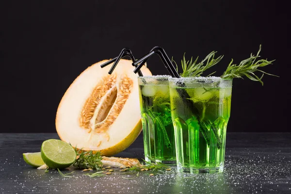Orzeźwiające napoje bezalkoholowe. Pokroić melona i zielone koktajle na czarnym tle. Słodkie napoje z alkoholem, wapno i estragonem. — Zdjęcie stockowe
