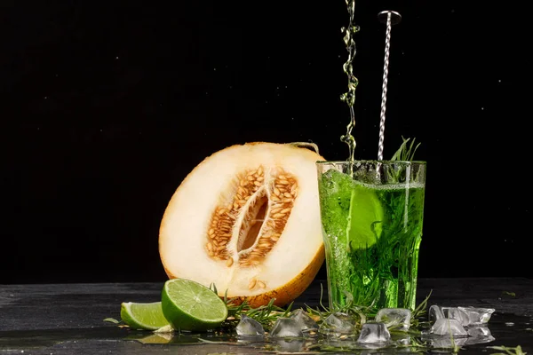 Una bebida verde con lima y estragón. Un cóctel y un melón sobre un fondo negro. Bebidas saludables, dulces y sabrosas. Copiar espacio . —  Fotos de Stock