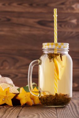 Bir büyük mason kavanoza sağlıklı yeşil limonlu çay. Kış içecek. Bir saman ile bir içki. Taze narenciye vitamin dolu. Kopya alanı.