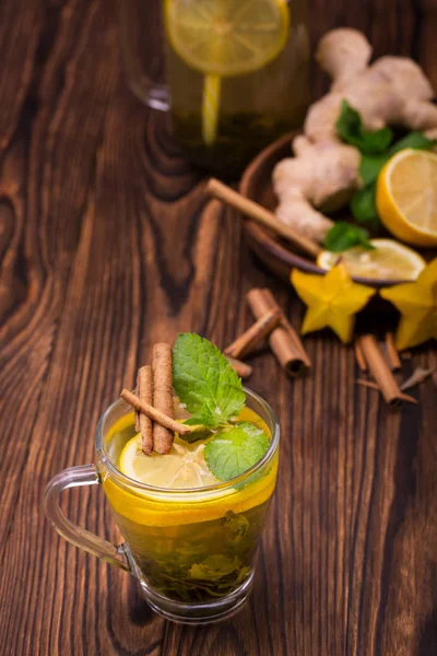 Vista superior de la taza de té de canela sobre un fondo de madera oscura. Una taza de té dulce con carambola, limón cortado, hojas de menta y canela . — Foto de Stock