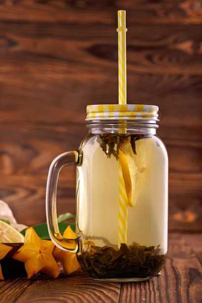 Οργανικό πράσινο λεμόνι τσάι σε ένα γυάλινο βάζο. Φθινοπωρινά ποτά. Ένα ποτό με ένα Καλαμάκι. Νωπά εσπεριδοειδή φρούτα πλούσια σε βιταμίνες. Χώρο αντίγραφο. — Φωτογραφία Αρχείου