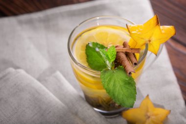 Gri kumaş arka plan üzerinde tarçınlı çay close-up. Şekerli bir çaya dekoratif carambola, nane yaprakları ve tarçın ile. Kopya alanı.