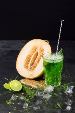 Bir içecek ve bir siyah arka plan üzerine bir kavun. Kireç ve tarhun ile kokteyl yeşil. Sağlıklı, tatlı ve lezzetli içecekler. Kopya alanı.