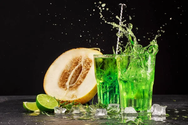 İki parlak tarhun sıçramasına kokteyller siyah bir zemin üzerine close-up. Tarhun, içecekler kesmek tatlı kavun, buz küpleri ve Ekşi limon.
