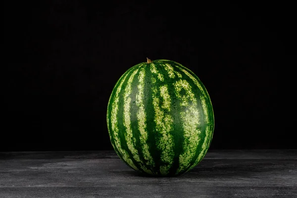 Imagem de close-up de uma melancia listrada redonda fresca e perfeita em um fundo preto. Alimentos saudáveis e orgânicos. Espaço de cópia . — Fotografia de Stock