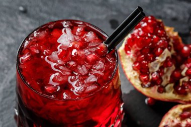 Bir lezzetli ve taze garnet içki buz siyah bir arka plan ile büyük bir bardak. Taze, olgun ve doğal kırık Granat bir tablo. Organik maddeler.