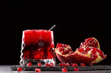 Taze sıkılmış nar suyu buz küpleri ile siyah bir arka plan üzerinde. RIPE, sulu, organik ve parası garnet meyve. Sağlıklı yaşam tarzı.