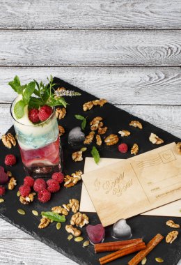 Güzel bir kompozisyon güzel kartpostallar ve ışık gri arka plan üzerinde renkli kokteyl. Birçok çilek, ceviz, tarçın ve yeşil yaprakları davetiye.