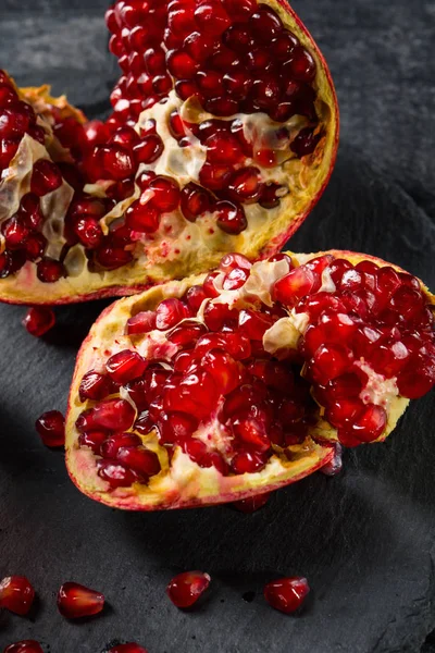 El granate dulce, fresco y natural para postres y bebidas sobre un fondo negro. Granada roja brillante se descompone en partes . — Foto de Stock