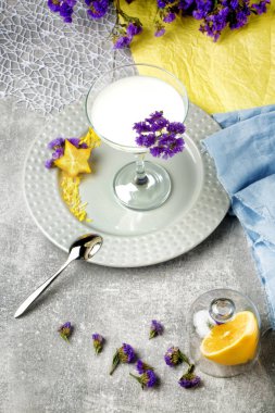 Yukarıdan bir margarita cam yukarıda renkli arka plan üzerinde taze, tatlı ve organik süt içecek dolu. Sulu, olgun limon ve bir kumaş üzerine güzel çiçekler.