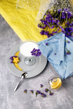 Yukarıdan bir margarita cam yukarıda renkli arka plan üzerinde taze, tatlı ve organik süt içecek dolu. Sulu, olgun limon ve bir kumaş üzerine güzel çiçekler.