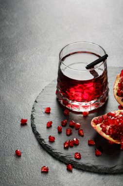 Parlak garnet içki ve hafif gri arka plan üzerinde kırmızı, ekşi nar. Yaz kokteylleri için egzotik malzemeler. Kopya alanı.