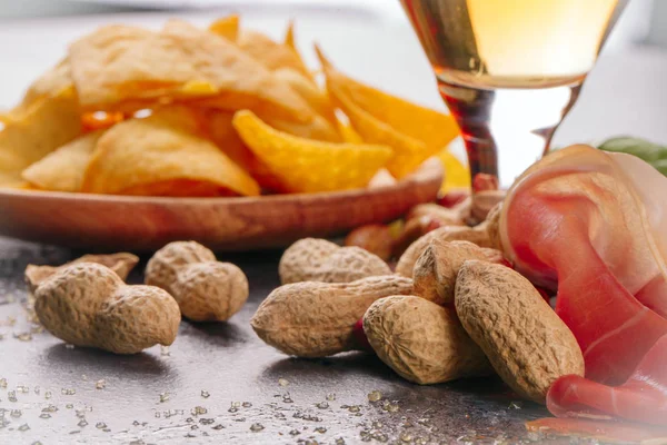 Close-up de uma cerveja leve fresca e fria e muitos lanches salgados em um fundo cinza desfocado. A bebida alcoólica e aperitivos na mesa . — Fotografia de Stock