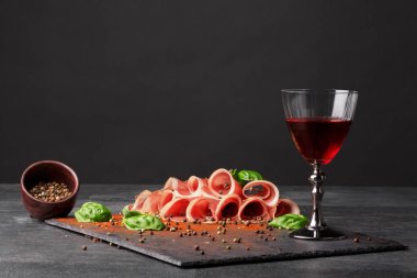 Gastronomi kompozisyon. Bir dolu bardağı, tuzlu jamon ve siyah bir zemin üzerine yeşil ıspanak. Soğuk alkollü içecekler. Kopya alanı.