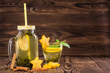 Ahşap arka plan üzerinde Çin çay bir mason kavanoz. Bir fincan yeşil çay. Limonlu çay egzotik baharatlar ile. Kopya alanı.