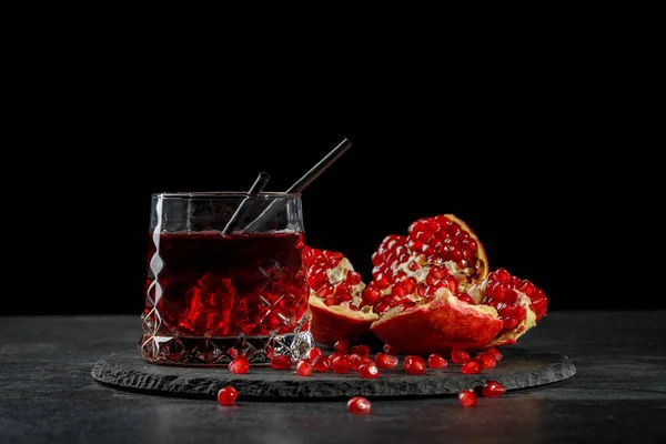 Ett glas berry god cocktail. Röd granat frön. Fräsch naturlig dryck och en mogen granatäpple på svart bakgrund. Kopiera utrymme. — Stockfoto