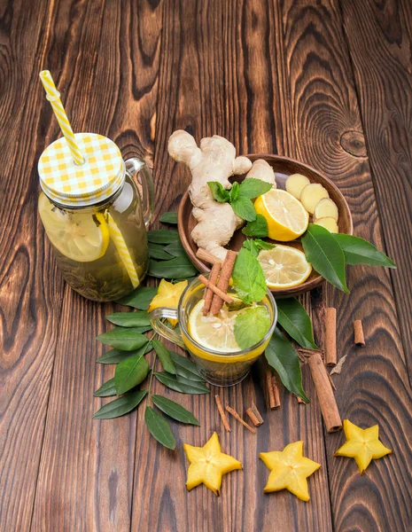 Top view of mason jar with hot beverage on a dark wooden background. Carambola, leaves , lemon, ginger, and cinnamon. Copy space.