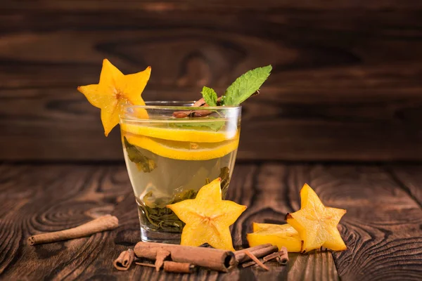 Hermosa taza de té. Té verde sobre fondo de madera. Té de menta con limón, carambola decorativa, canela. Copiar espacio . — Foto de Stock