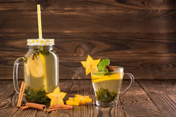 Un frasco de té chino sobre un fondo de madera. Una taza de té verde dulce. Té de limón con especias exóticas. Copiar espacio . — Foto de Stock