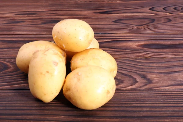 Großaufnahme einer neuen Kartoffel auf einem Holztisch, frisches Gemüse voller Vitamine auf dunklem Holzgrund. — Stockfoto