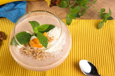 Meyveli smoothie tatlı gözlüklü sarı bir arka plan üzerinde. Kokteyl ile kuru kayısı, dondurma ve muz, ana sayfa görünümü.