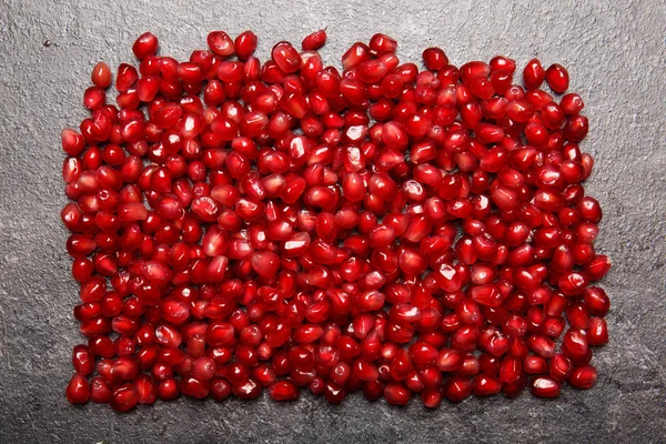 Группа гранатовых зерен на сером фоне. Верхний вид ярко-красного граната. Сочные семена красного граната. Натуральные фруктовые ингредиенты для здоровых соков . — стоковое фото