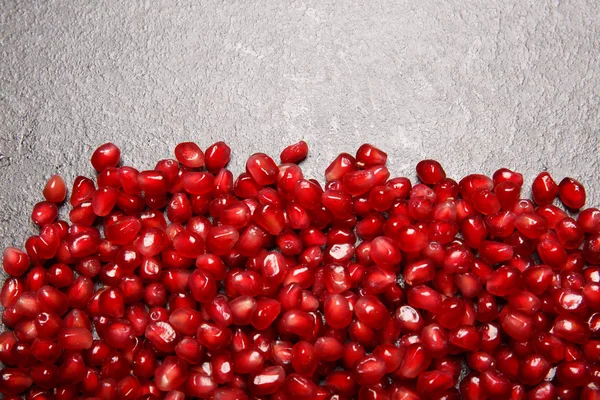 Garnet seeds on a stone background. Top view of red pomegranate seeds on a table. Agricultural background. Copy space. — Stock Photo, Image